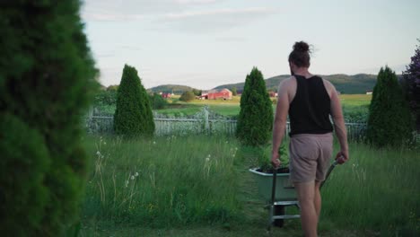 person at the lawn yard pushing wheelbarrow with potted plants in rural village