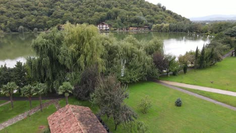 Aerial-view-of-lake-surrounded-by-mountains-green-trees-forest