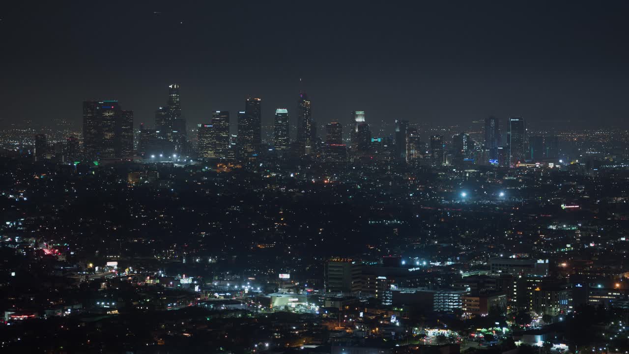 Timelapse drone view of Los Angeles at night, with glowing skyscrapers and bustling streets. A dynamic aerial sweep captures the city’s electric energy, iconic skyline, and cinematic urban pulse