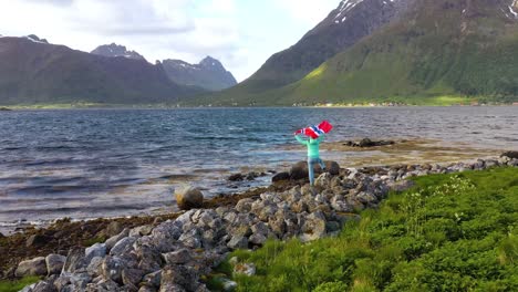 mujer con una bandera de noruega ondeando en el fondo de la naturaleza