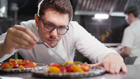 chef adding garnish to salad with tweezers