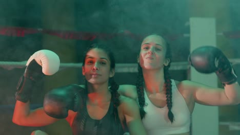 two confident female boxers in braided pigtails sitting near the ring, looking at the camera and showing biceps