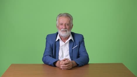 hombre de negocios barbudo y guapo contra un fondo verde.