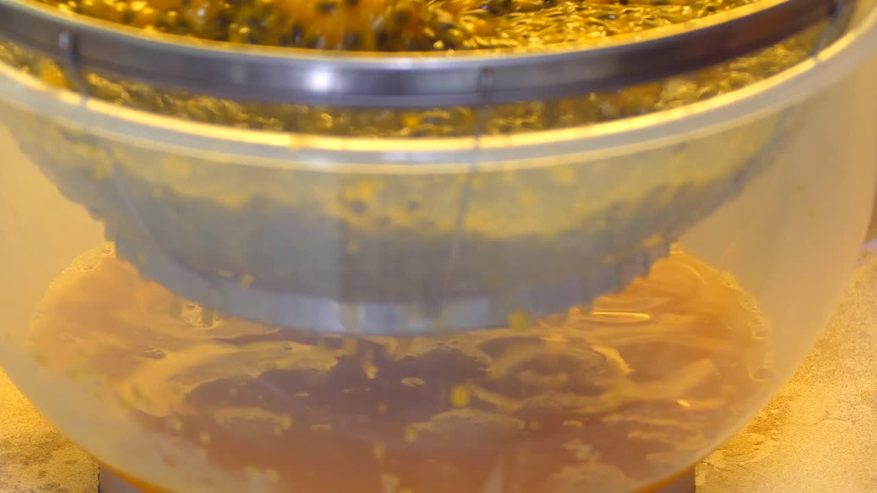Stirring passion fruit pulp to separate the juice through a sieve into a bowl