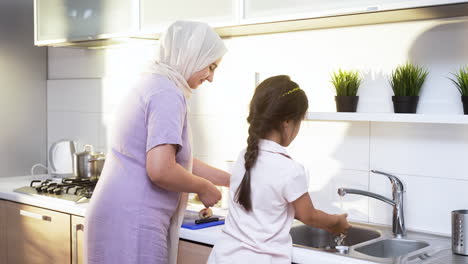 mother with hiyab and daughter in the kitchen.