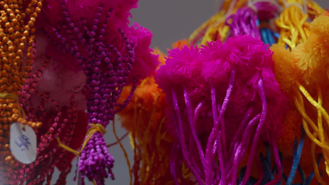 different colors of cotton ball rakhis in bunch hanging on on shop for sale during Raksha Bandhan Festival in India , 4k,pan, closeup, 25p