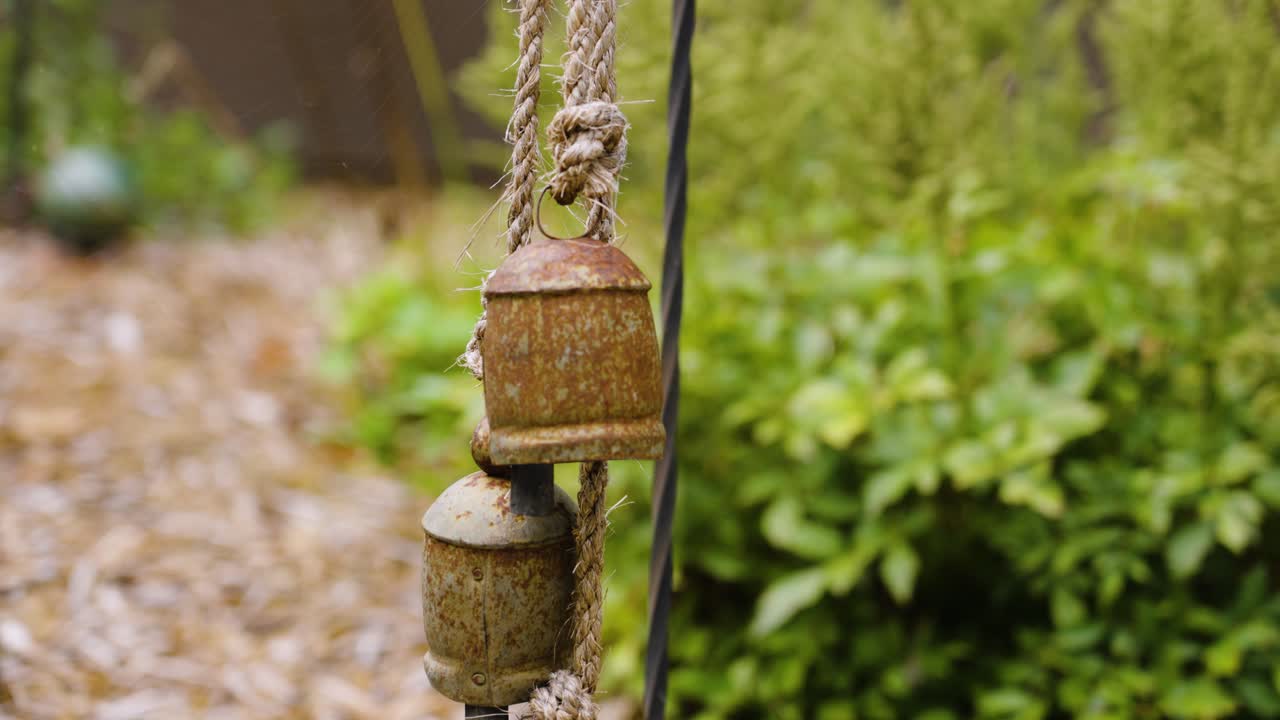 Camera slow motion footage with color look at decorative bells in a garden.