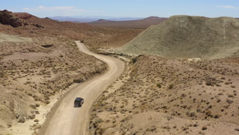 Schwarzes-Geländewagen-4x4-Beschleunigt-Einen-Trockenen-Feldweg-In-Der-Wüste-Hinunter-Und-Hinterlässt-Eine-Staubspur