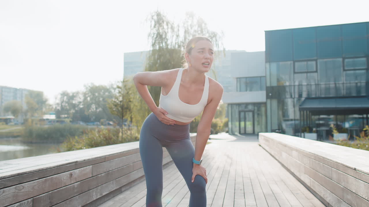 은 날 도시 공원에서 달리기하는 동안 복통으로 고통받는 젊은 백인 달리기 선수