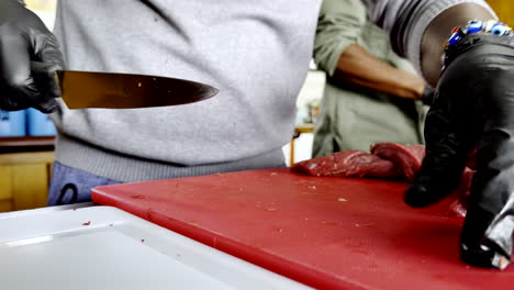 african chef with traditional jewellery, skilfully cuts meat with precision