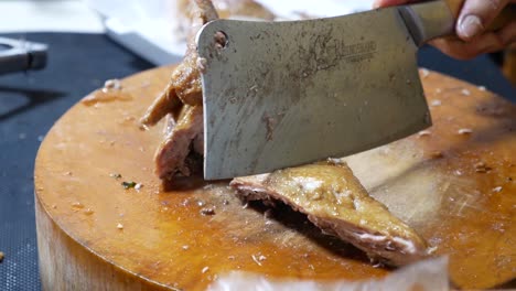imágenes de primer plano del vendedor de comida callejera cortando pato estofado chino en una tabla de cortar de madera