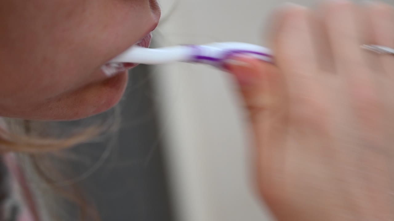 Close up of a woman brushing her teeth in the morning