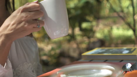 una mano femenina levantando graciosamente una taza de café durante el desayuno