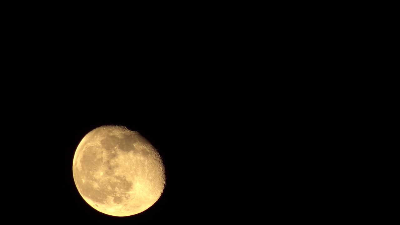 어두운 하늘 배경에서 왼쪽에서 오른쪽으로 떠오르는 만월의 쇠약한 달