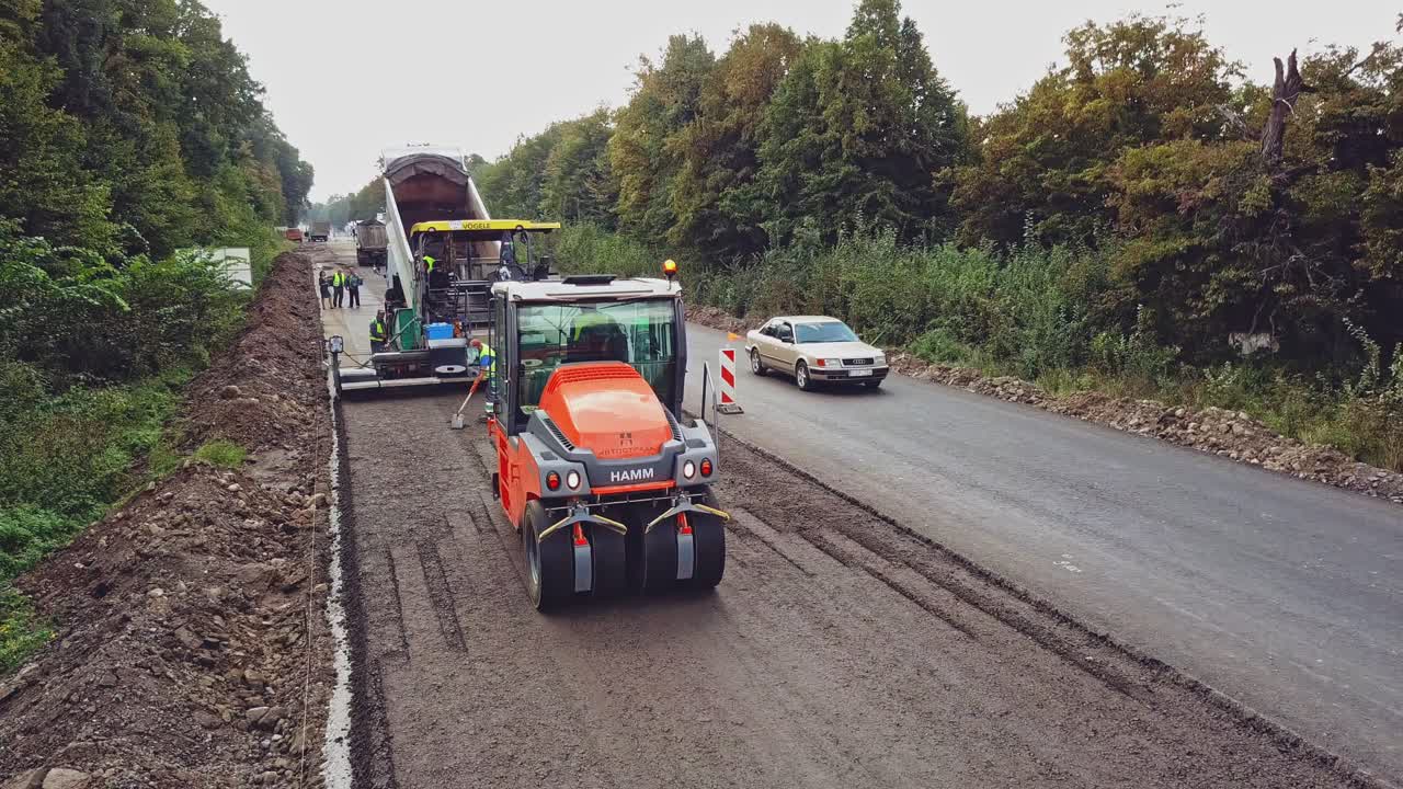 Road construction works with roller compactor machine and asphalt finisher. Construction of the road. Aerial view