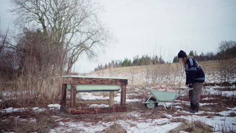 the man moves bricks from the wheelbarrow and places them next to the diy hot tub - static shot