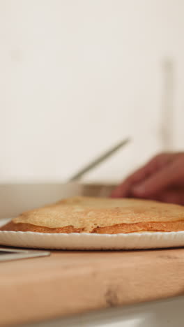 senior woman takes plate with pancakes and carries food to dining room. caring grandmother cooks delicious homemade pastries for beloved relatives closeup