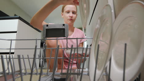 a child puts dirty plates in the dishwasher in the kitchen. view from inside the dishwasher