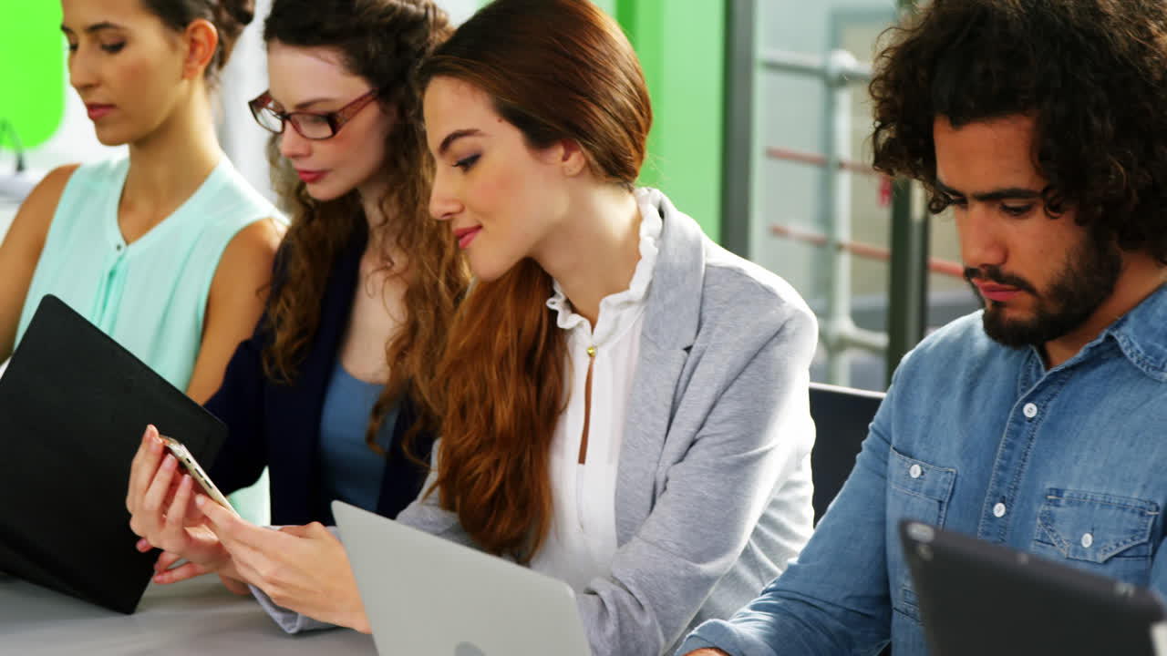 ejecutivos empresariales que utilizan portátiles, teléfonos móviles y tabletas digitales en las reuniones