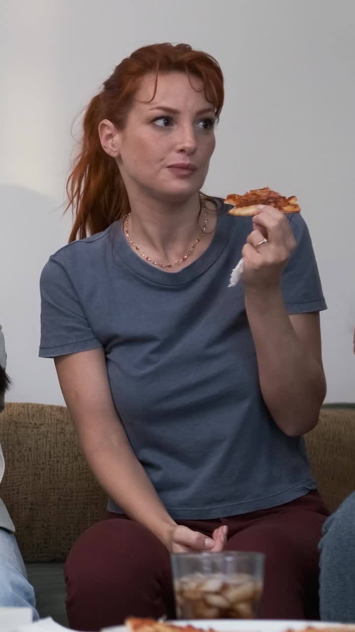 Diverse friends cheering up for woman bringing pizzas during weekend party at home