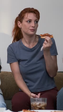 Diverse friends cheering up for woman bringing pizzas during weekend party at home