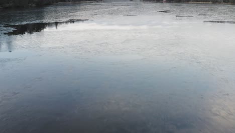 Sunrise-aerial-flight-over-melting-ice-on-surface-of-lake