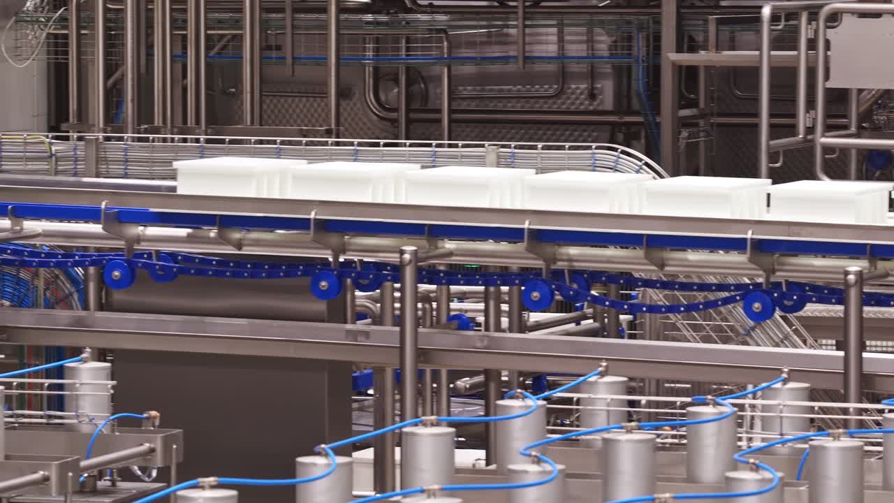 Industrial conveyor system with white bins moving through bright clean processing area
