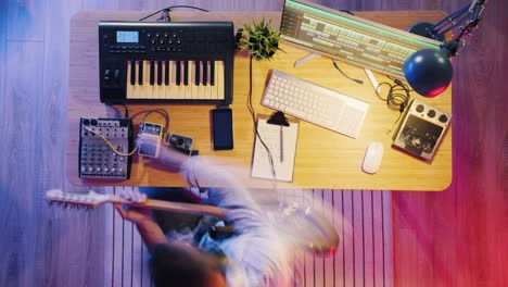 top view time lapse of male musician recording music with electric guitar and keyboard at night