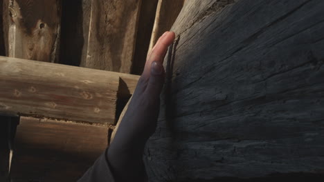 hand touching a weathered wooden beam