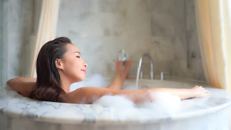 beautiful brunette woman relaxing in kingsize warm foamy bath slomo