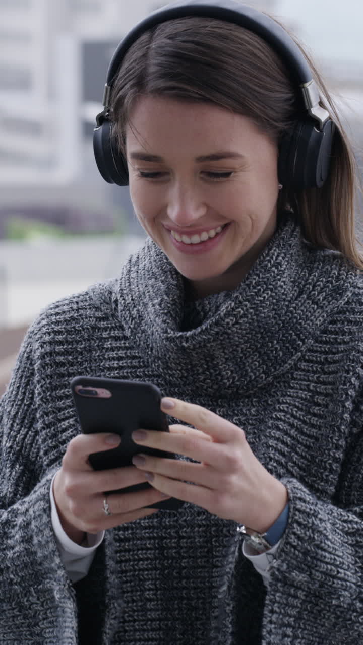 Giovane donna sorridente che usa lo smartphone con le cuffie all'aperto