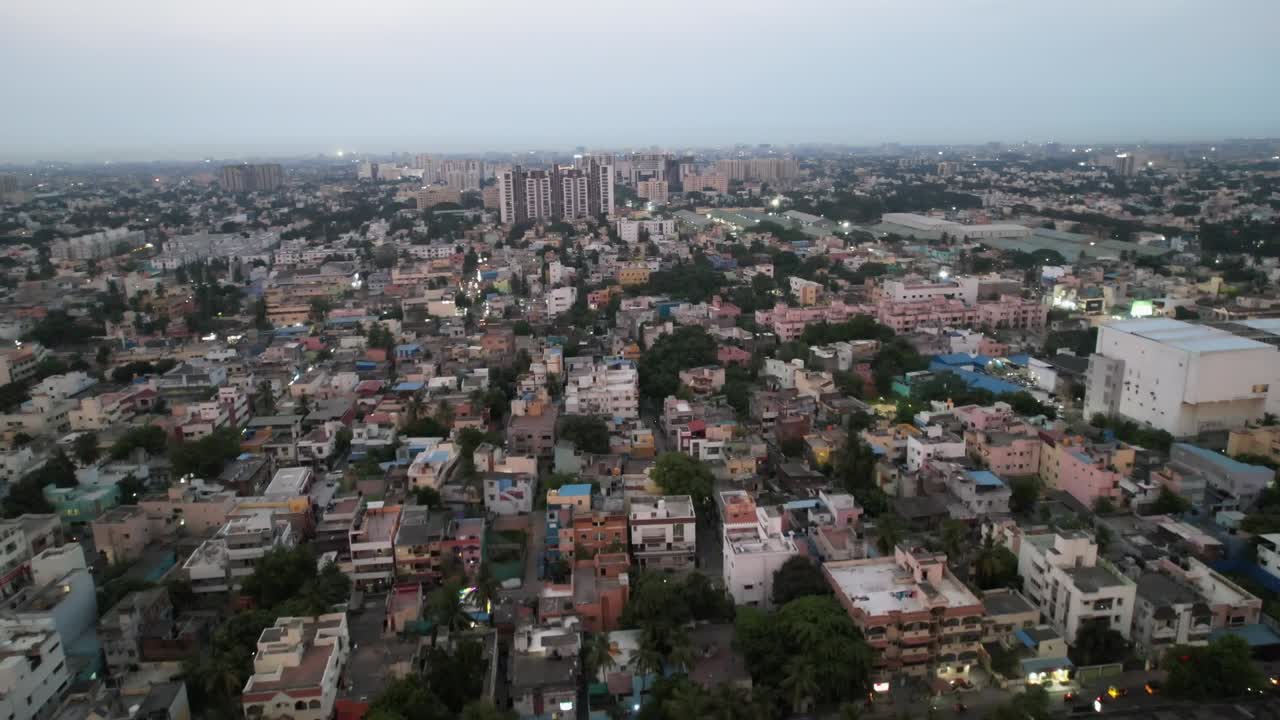 un barrio lleno de gente en la ciudad de chennai se ve desde arriba en la noche, junto con edificios de gran altura y la construcción de trenes de metro