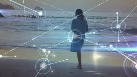 animación de redes de conexiones sobre mujer caucásica caminando por la playa
