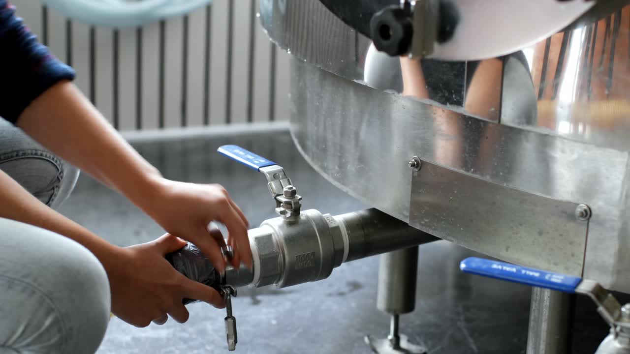 trabajadora chequeando una tubería en una fábrica de destilería 4k
