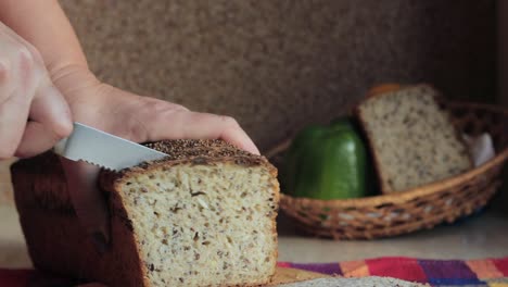 primer plano en cámara lenta centrándose en las manos de la mujer usando un cuchillo de pan y cortando un pan casero de grano entero