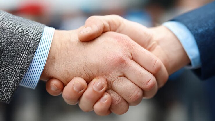 Un momento decisivo di unità: due mani che si stringono saldamente in segno di accordo e fiducia, a simboleggiare collaborazione e comprensione reciproca in contesti professionali