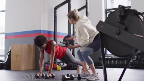 Vídeo-De-Diversas-Entrenadoras-De-Fitness-Instruyendo-A-Una-Mujer-Levantando-Pesas-Haciendo-Ejercicio-En-Un-Gimnasio