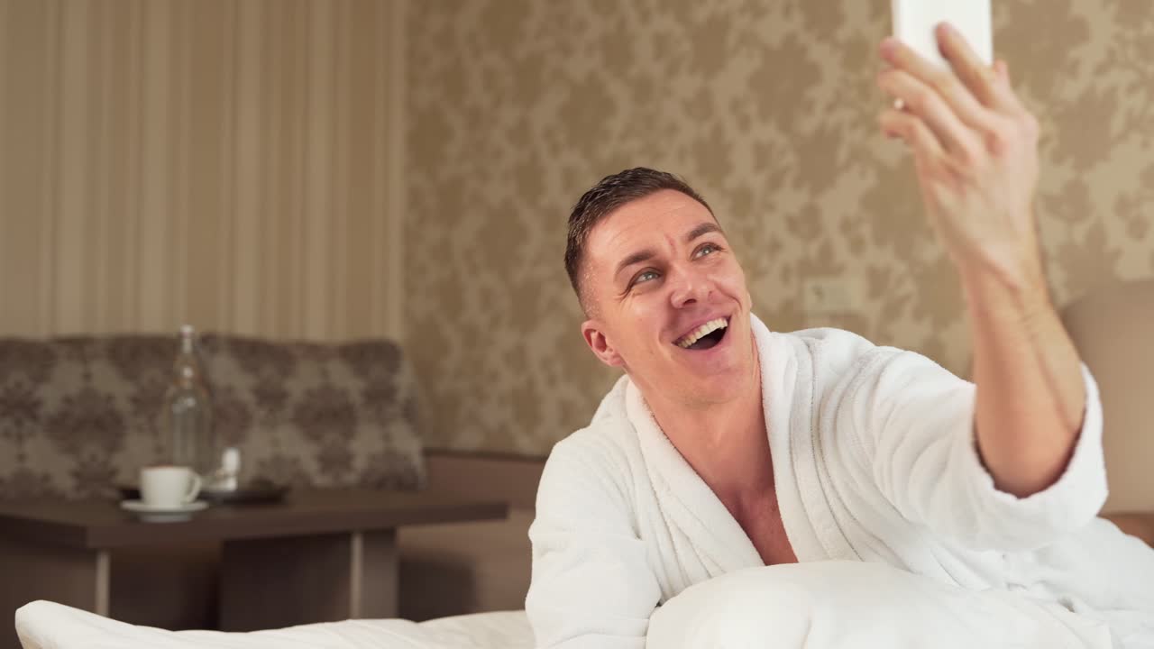 handsome sporty guy in robe takes selfie on phone