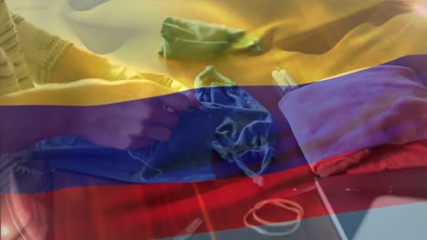 bandera colombiana ondeando contra la sección media de una mujer cosiendo una máscara facial