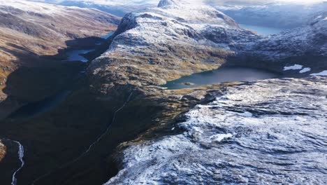 Hermoso-Paisaje-De-Montaña-Con-Una-Ligera-Capa-De-Nieve-Y-Varios-Lagos-Y-Cascadas,-Noruega,-Europa,-Drone