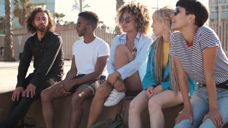 jóvenes amigos contentos relajándose en el paseo marítimo de la ciudad