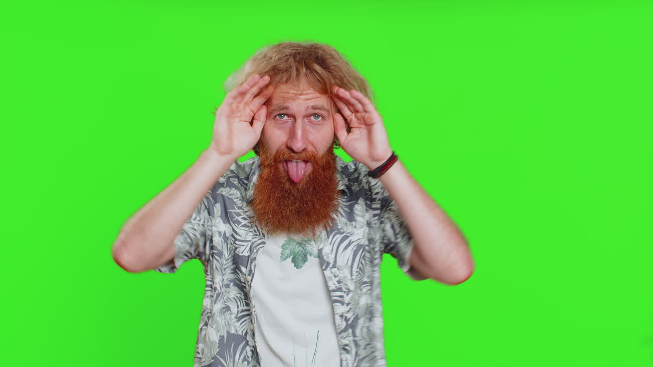 Funny comical young man making silly facial expressions grimacing fooling around showing tongue