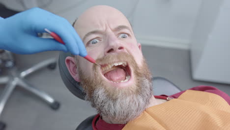 man opens mouth but panics as dentist brings syringe with anaesthetic closer