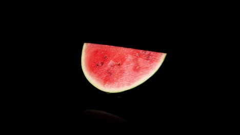 Spinning-piece-of-red-watermelon-in-studio-with-black-background