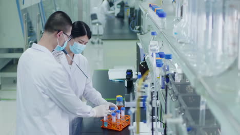 professional team researcher transferring solution samples to a tissue culture flask with suction pipette for cell culture assay in biological cabinet on in cleanroom environmental facility laboratory