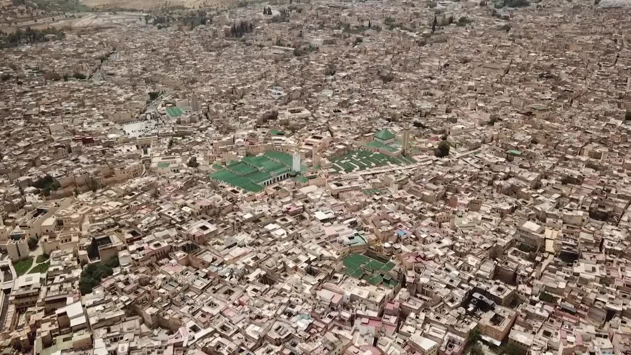 Breath-taking wide aerial view of the ancient Fez El Bali. Captures the immense architectural density, the green-roofed mosques, and the historic landscape of the world's largest car-free zone