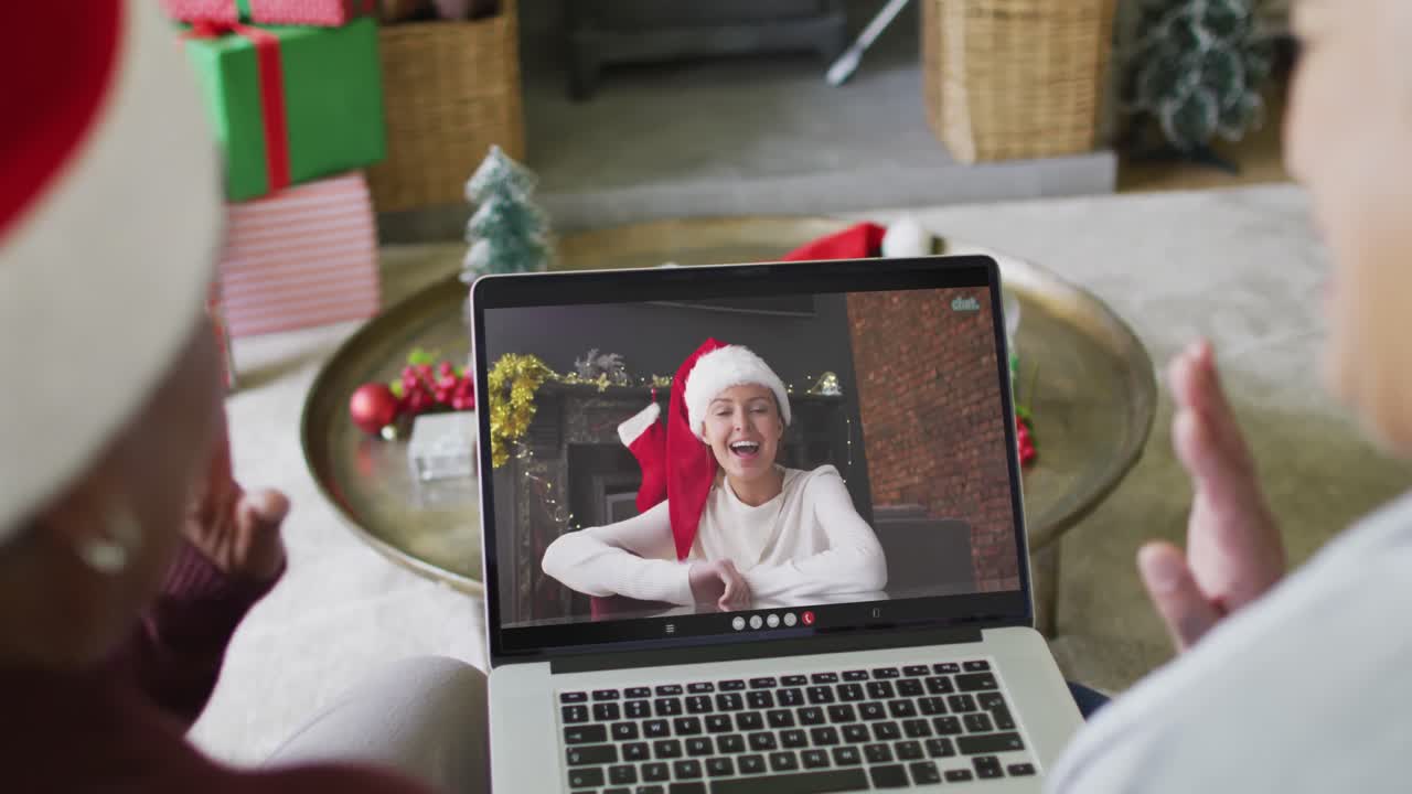 diversas amigas mayores que usan una computadora portátil para una videollamada de navidad con una mujer feliz en la pantalla