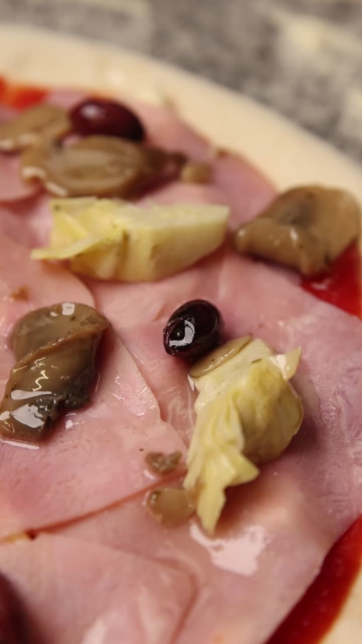 Primo piano di pizza cruda con prosciutto, funghi, carciofi e olive
