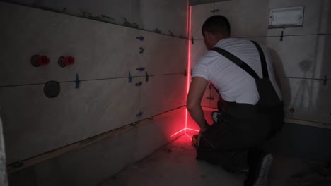 a tiler lays ceramic tiles on the floor using a construction laser