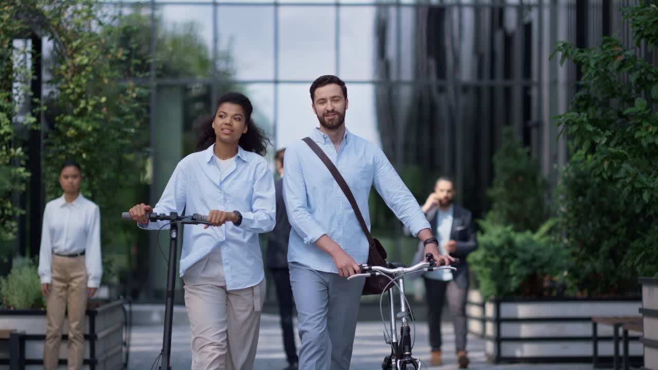 Smiling colleagues walking talking at downtown. Corporate eco-friendly culture.